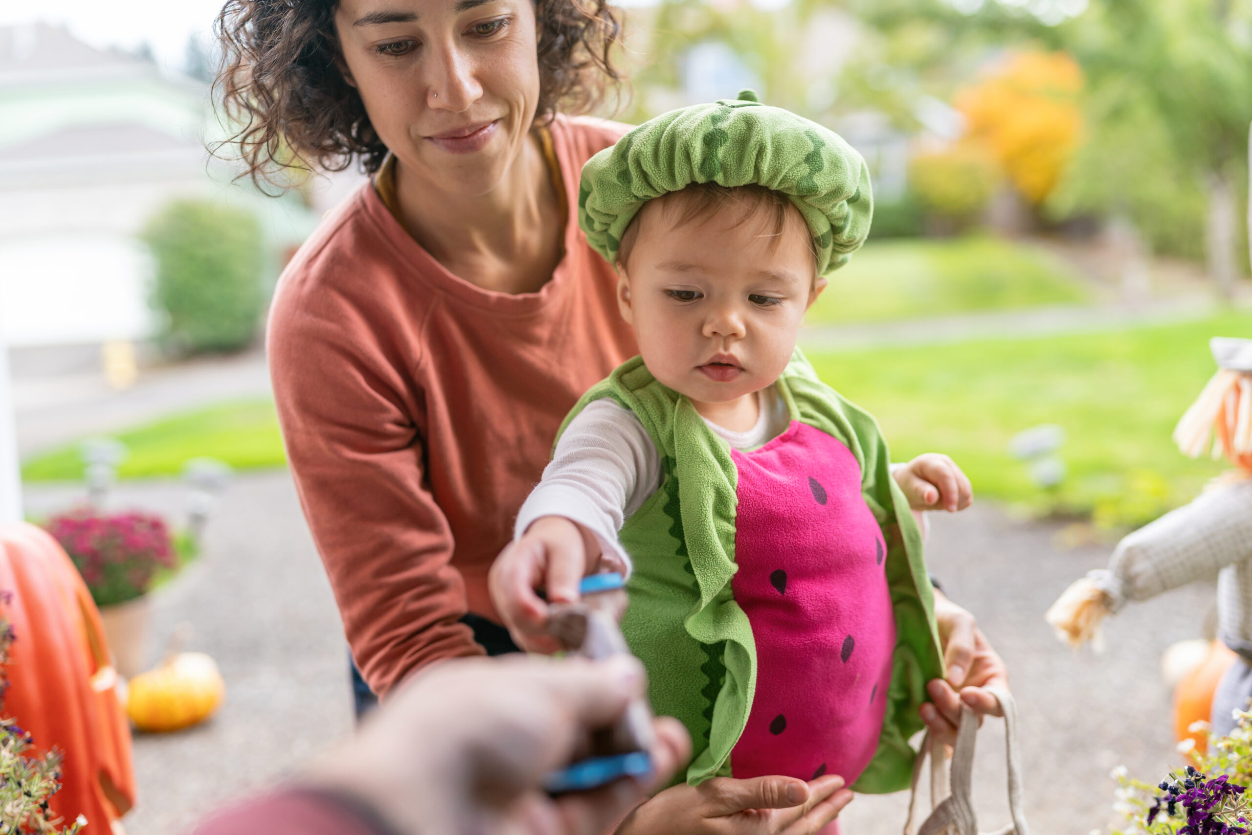 Adorable toddler trick or treating with her mom