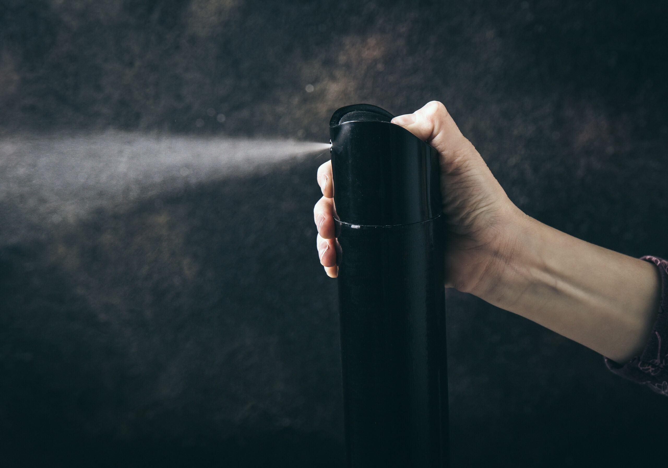 Conceptual image of chroming. Process of getting high using household chemicals to inhale. Child hand holding hairspray bottle and spray aerosol.