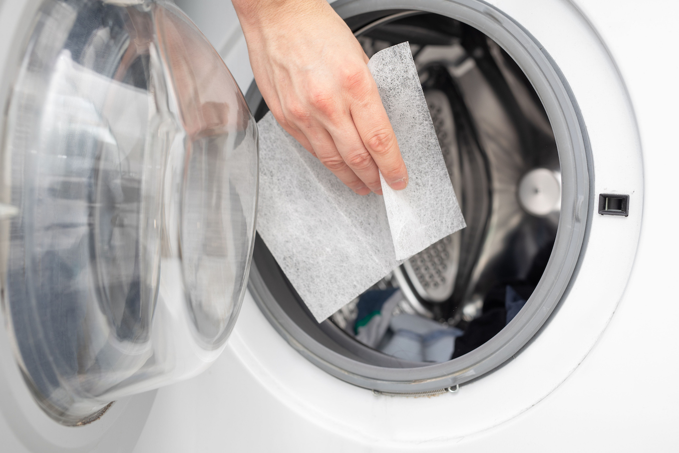 Hand dropping dryer aromatic sheets in a washing machine