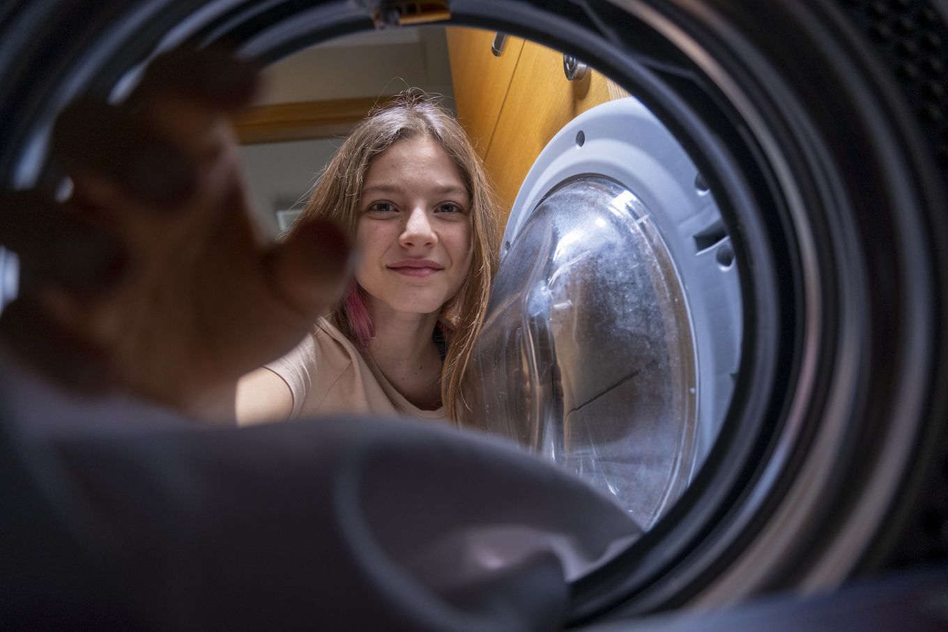 Young girl helping unload the washing machine at home