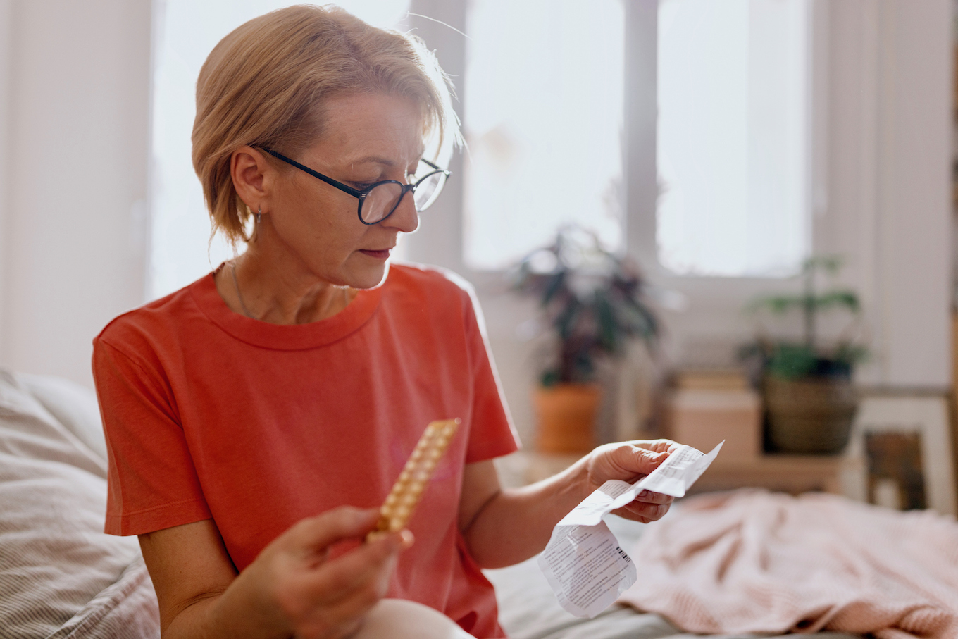 Woman reading a prescription that came with medicine pills for hormone replacement therapy