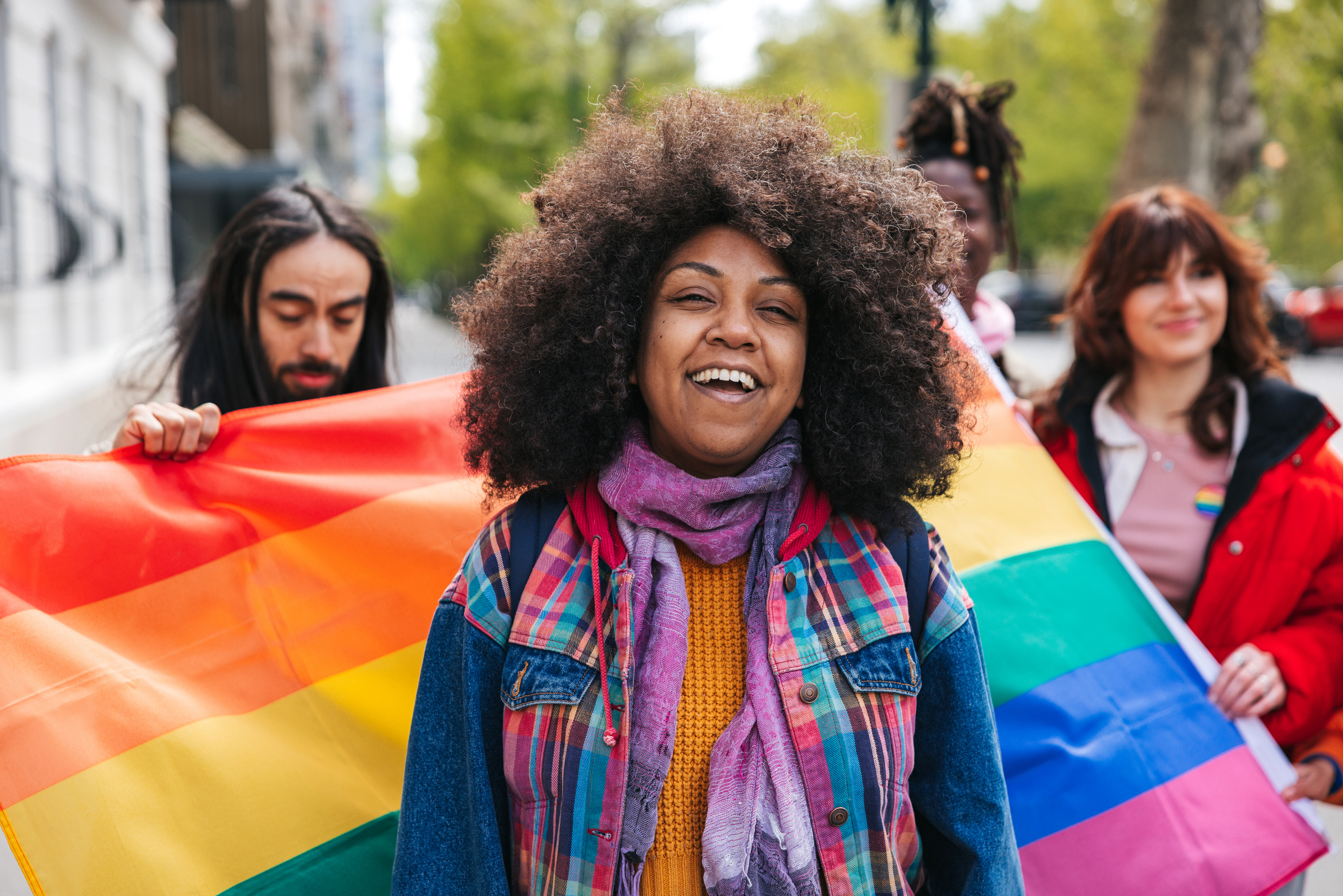 Woman with natural black hair Afro hairstyle posing in front a rainbow flags during a Pride Parade