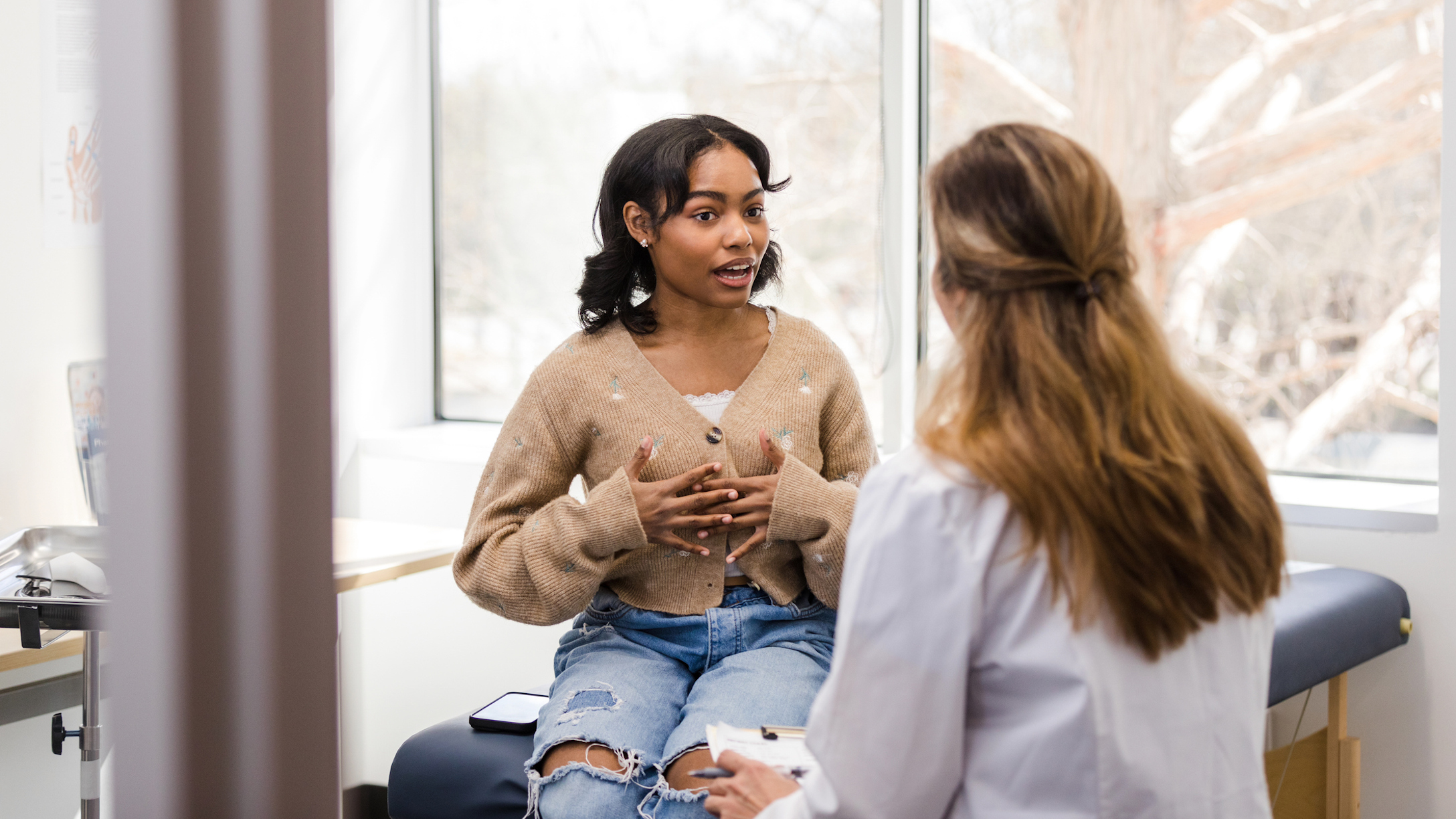 Young adult female patient gestures while explaining her mental health struggles with the doctor