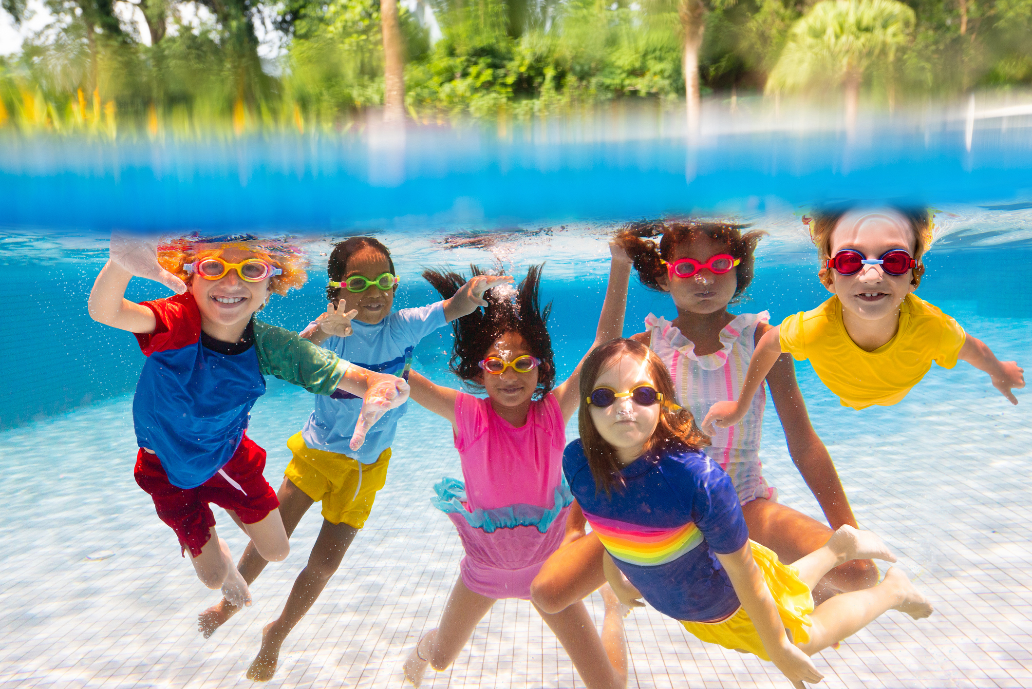 Kids jump into swimming pool. Summer water fun.