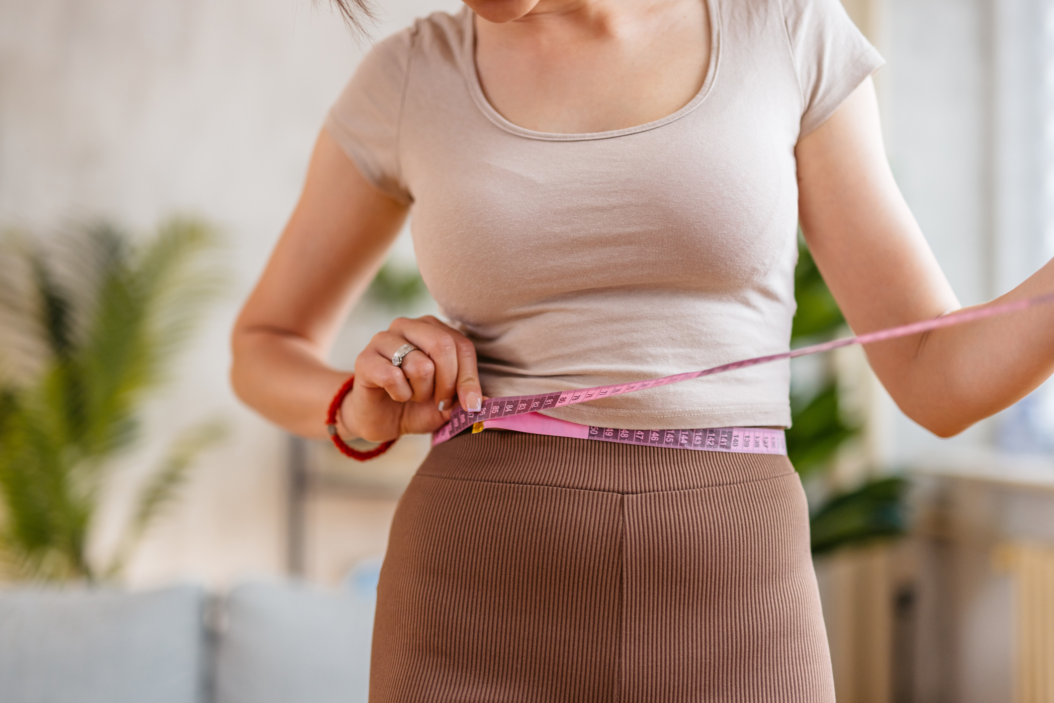 Young Woman Measuring Her Waist At Home