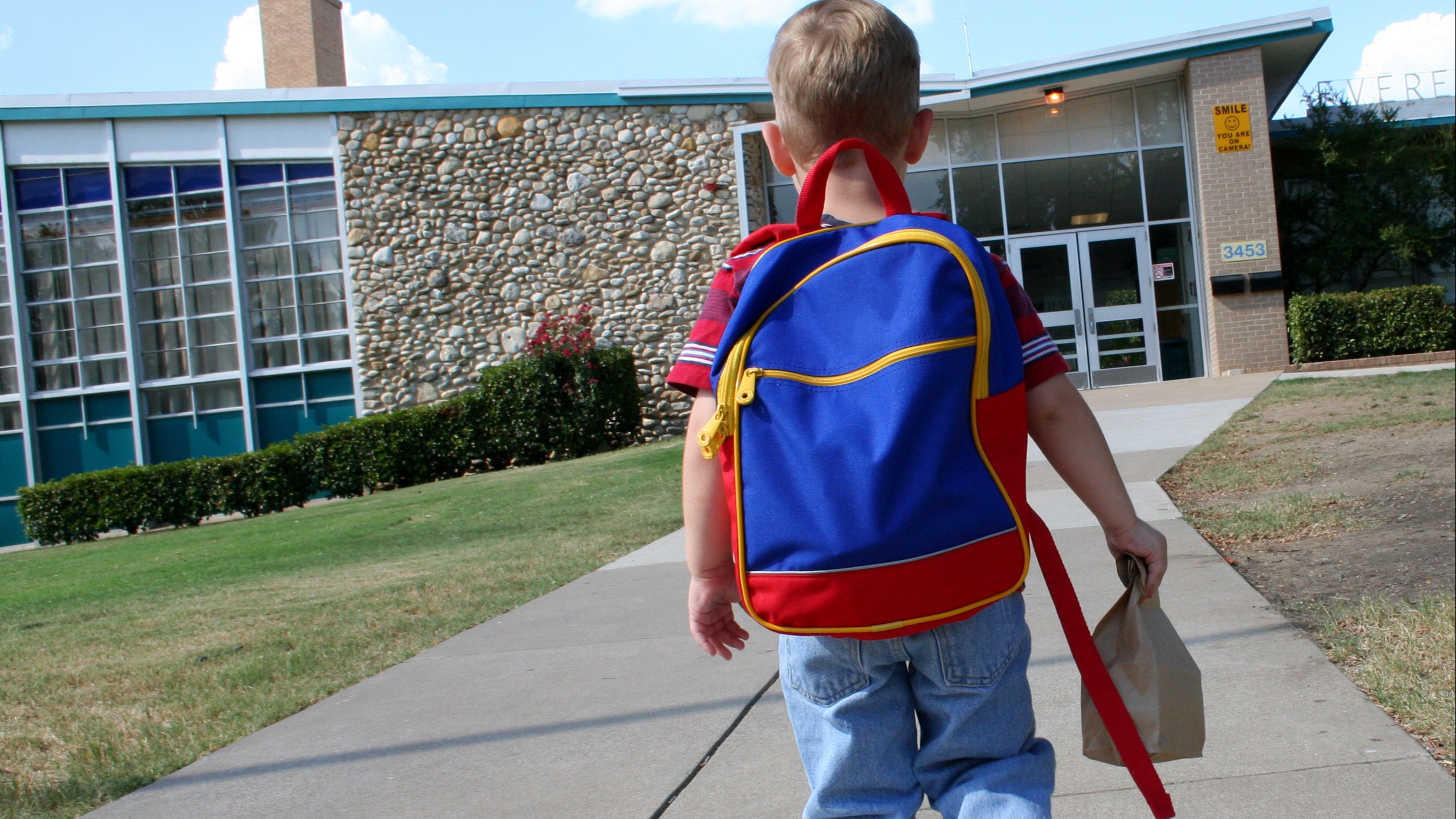 Kid walking up to school with lunch in hand