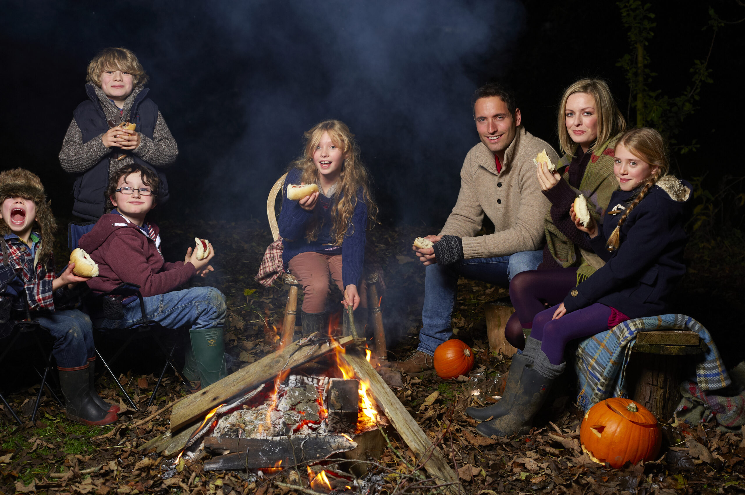 Family eating around campfire at night