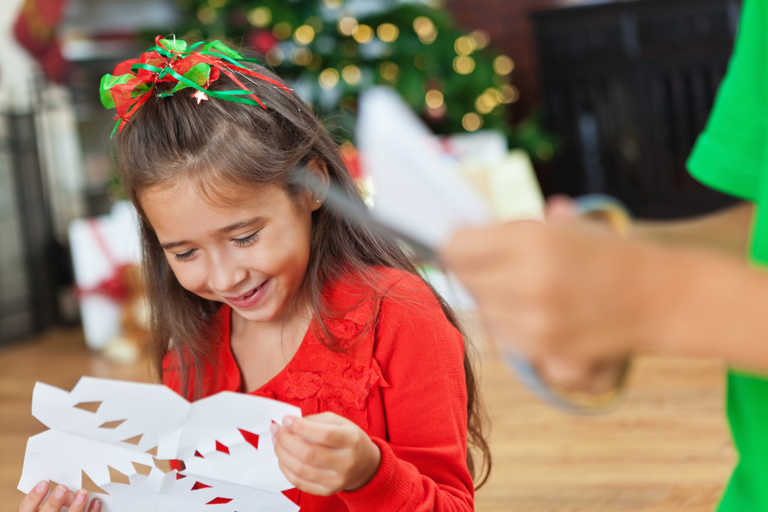 Siblings in red and green make Christmas snowflakes.