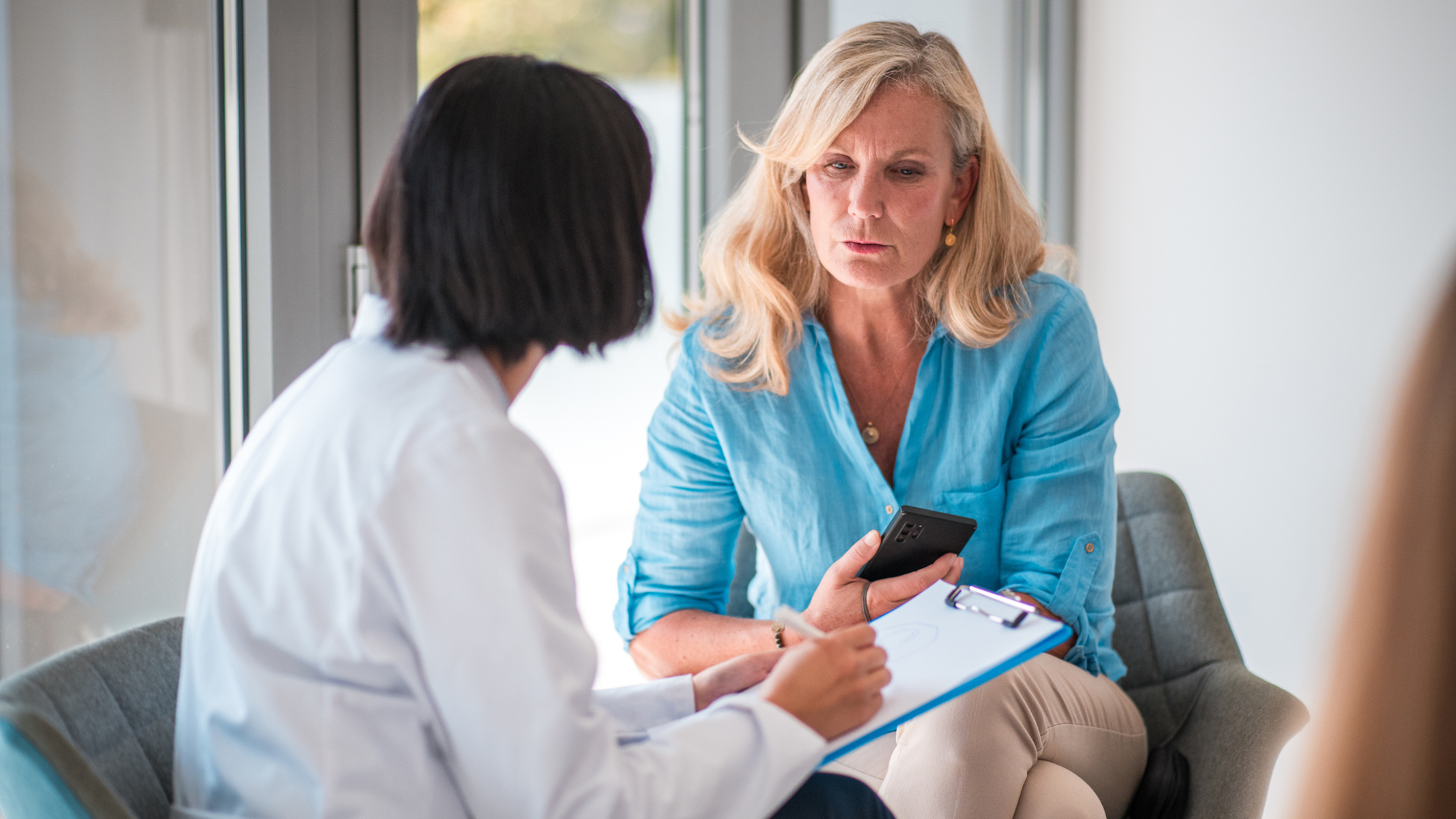 Mature Caucasian Female Patient and Asian Female Doctor in Doctor's Office