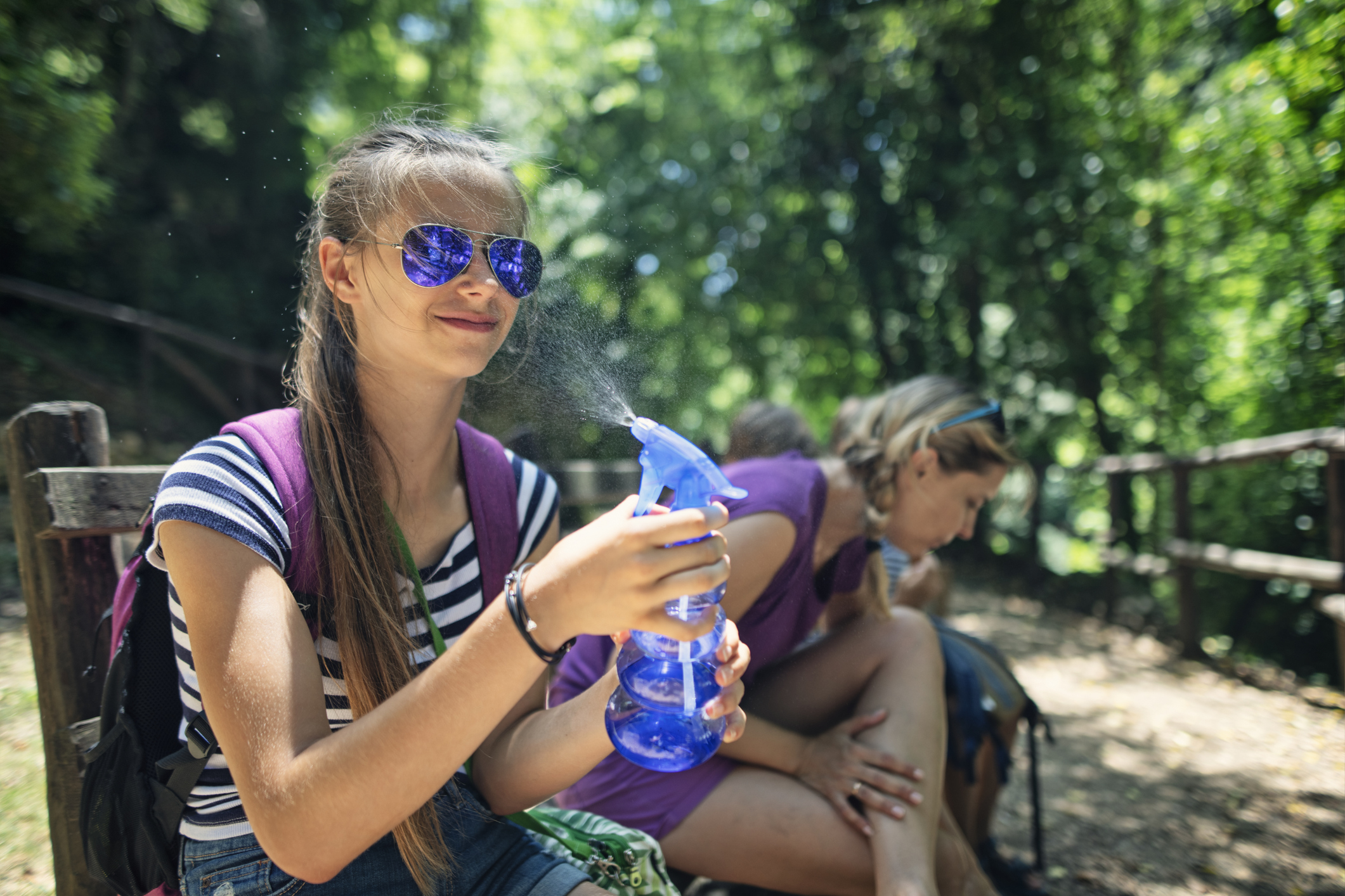 Teenage girl spraying her face with water while hiking in mountains of Campania, Italy