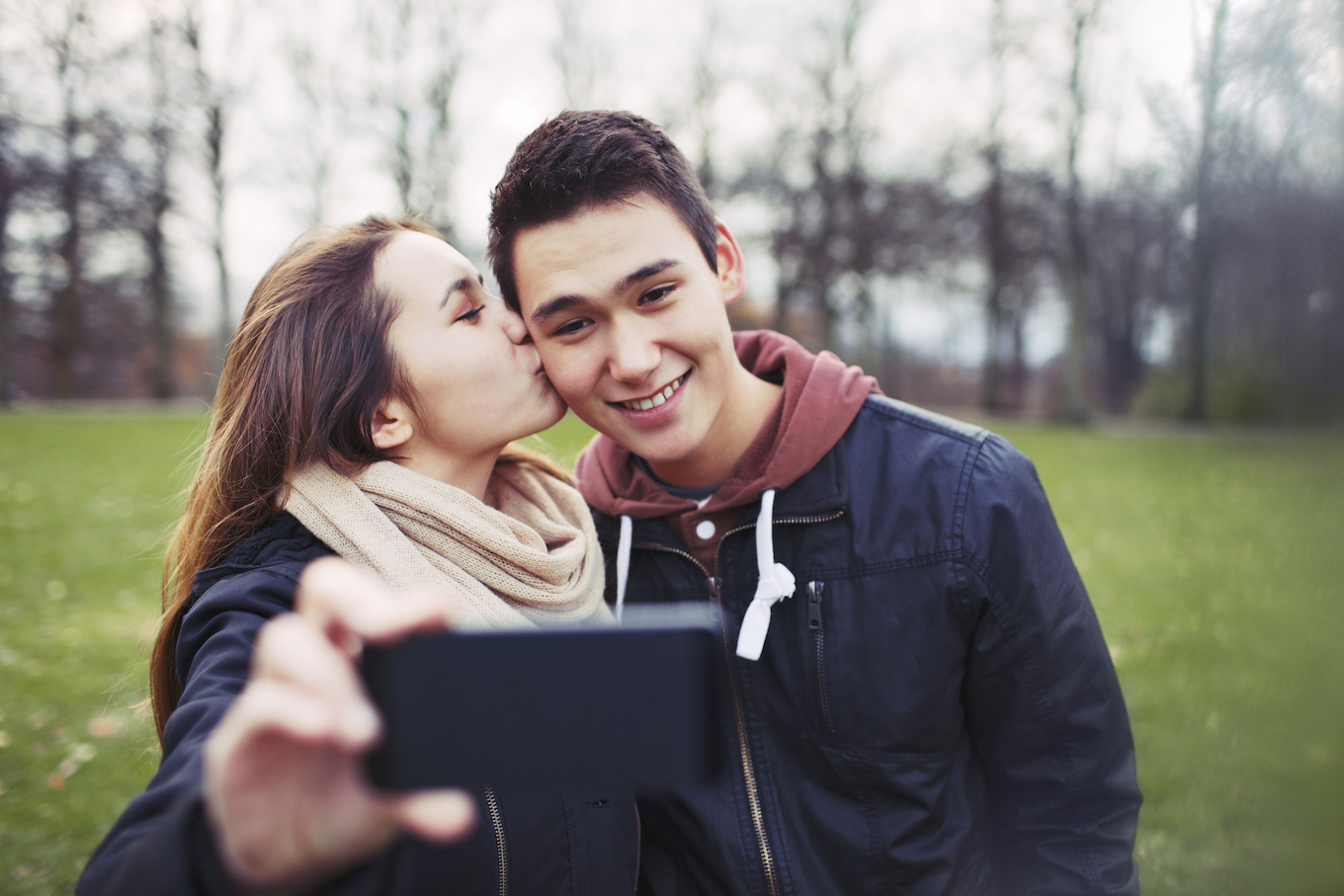 Loving teenage couple taking self portrait with a mobile phone