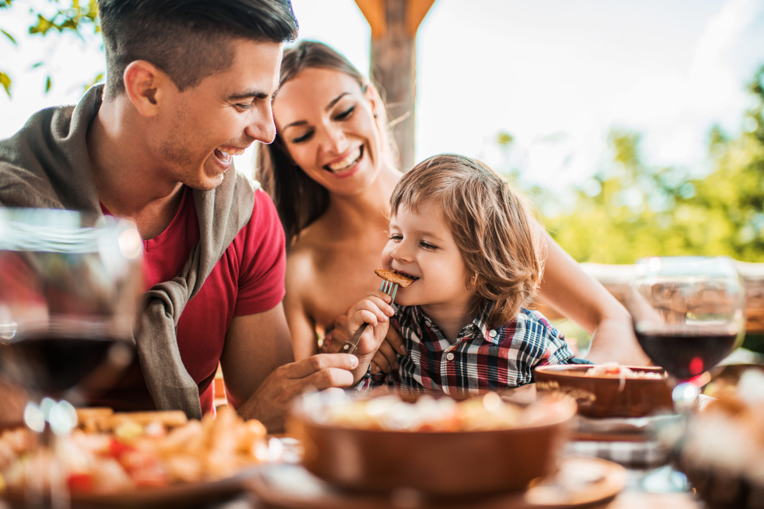 Cheerful young father feeding his son in restaurant.