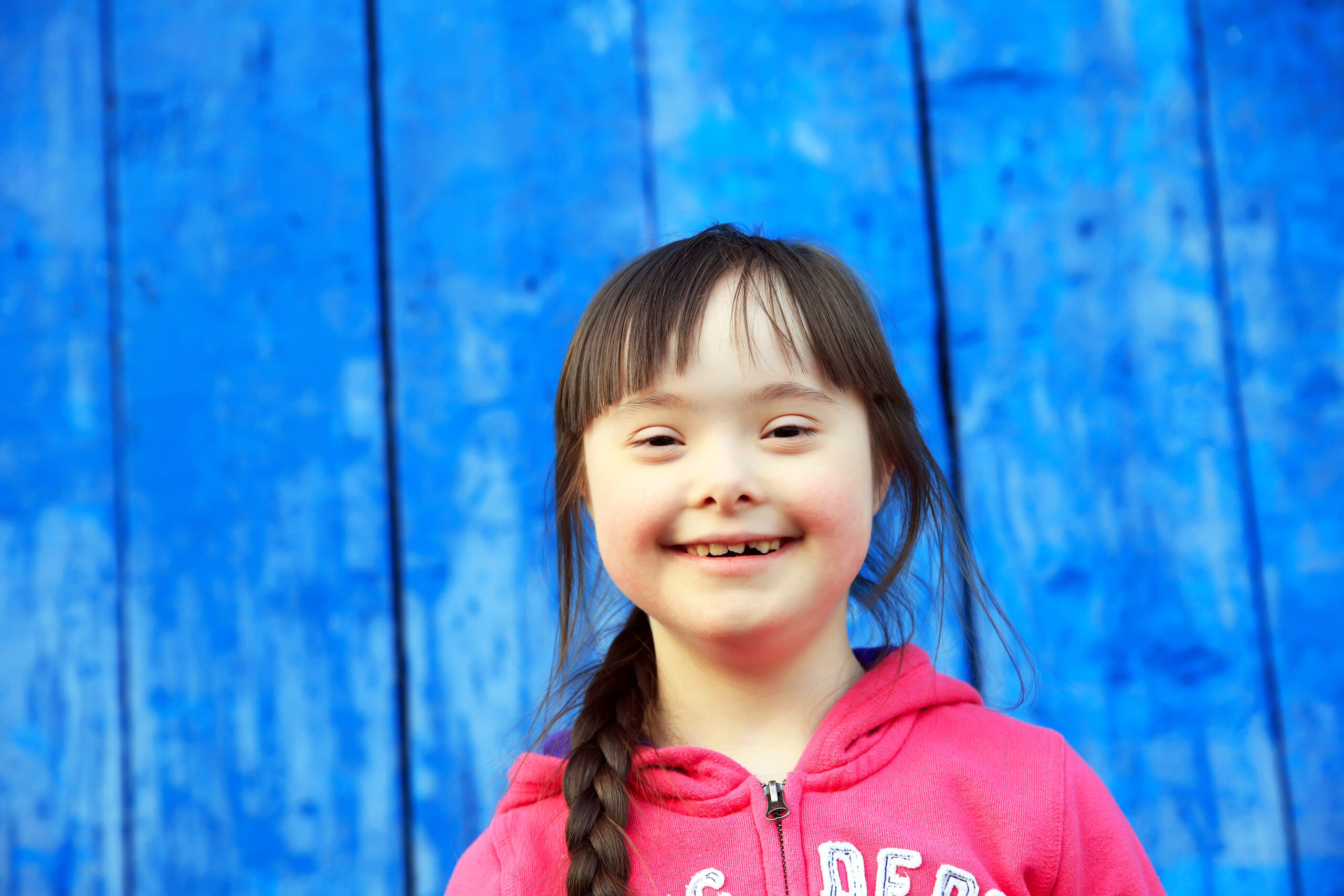 Young girl smiling on background of blue wall