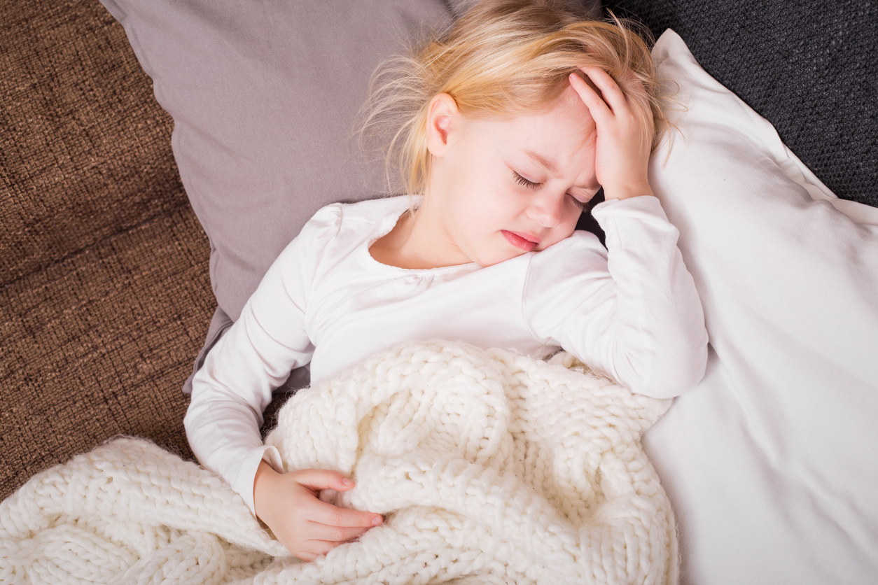 Little child being sick and holding her hand on forehead