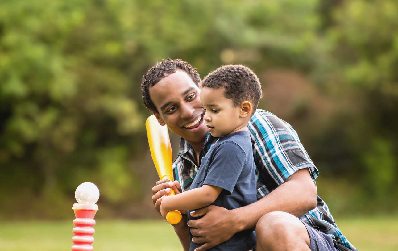 African American Father and Young Son outdoors playing T Ball