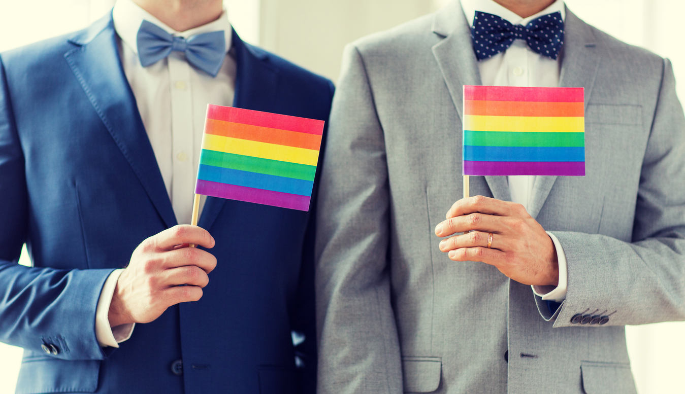 close up of male gay couple holding rainbow flags