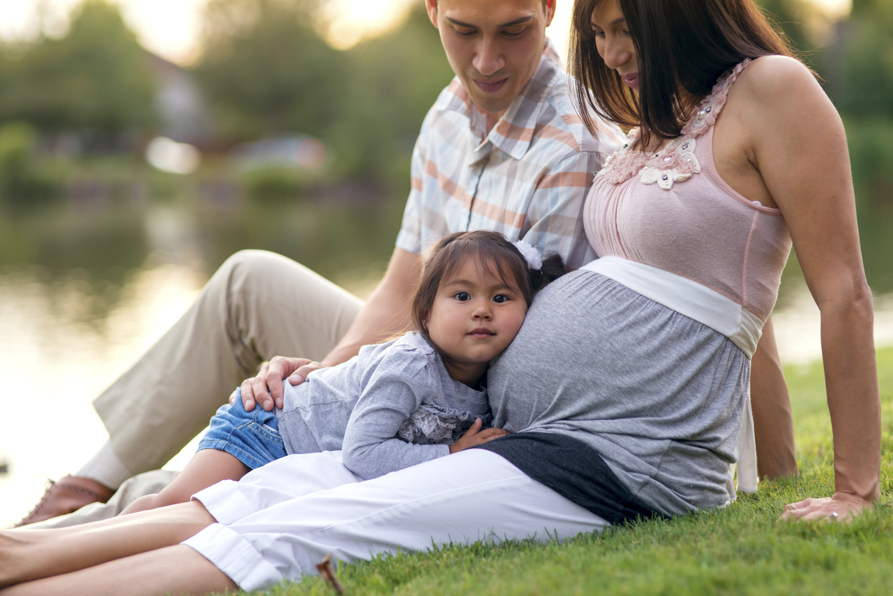 Cute young family sitting on the grass in a park