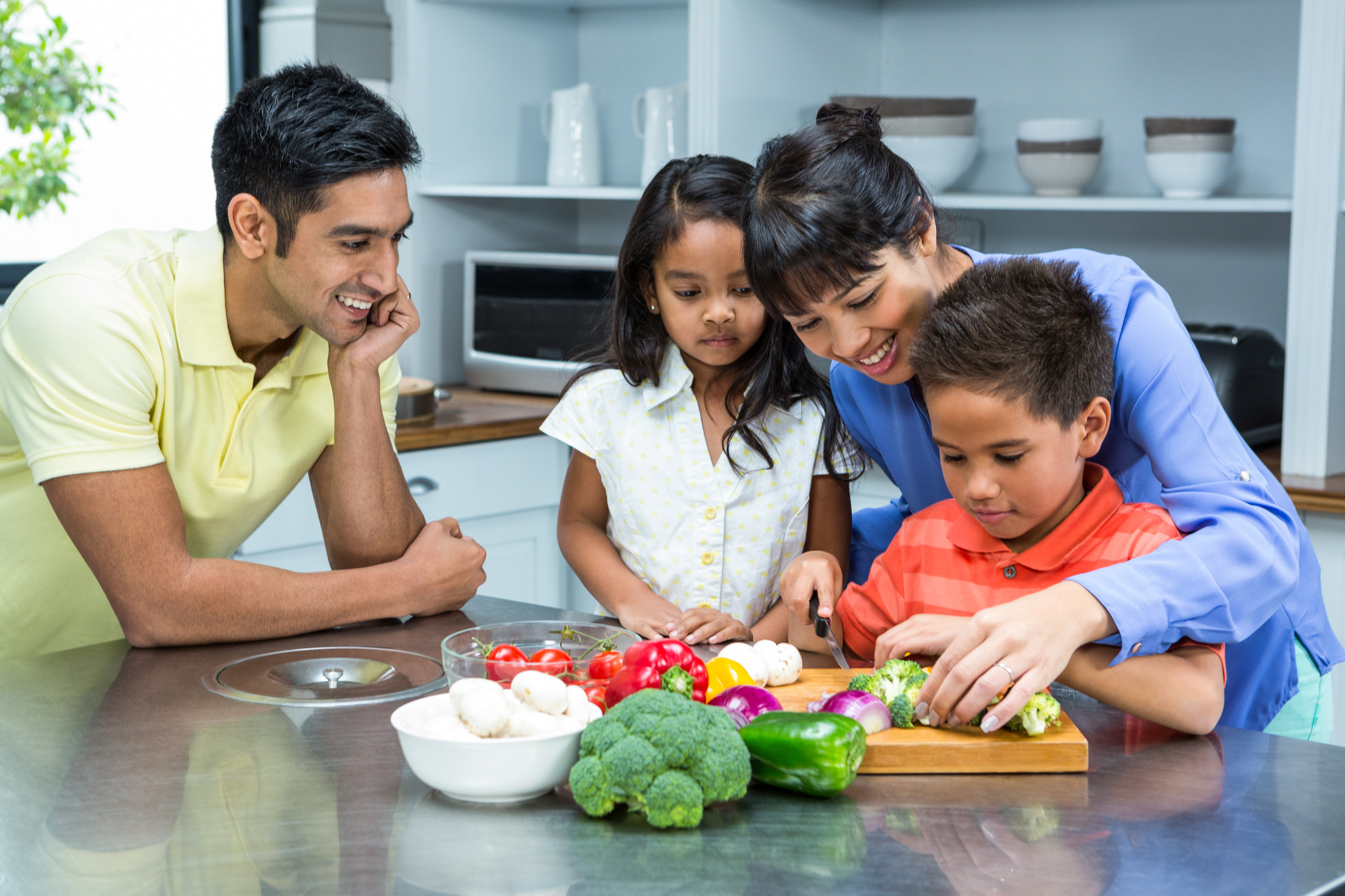 Happy family slicing vegetables