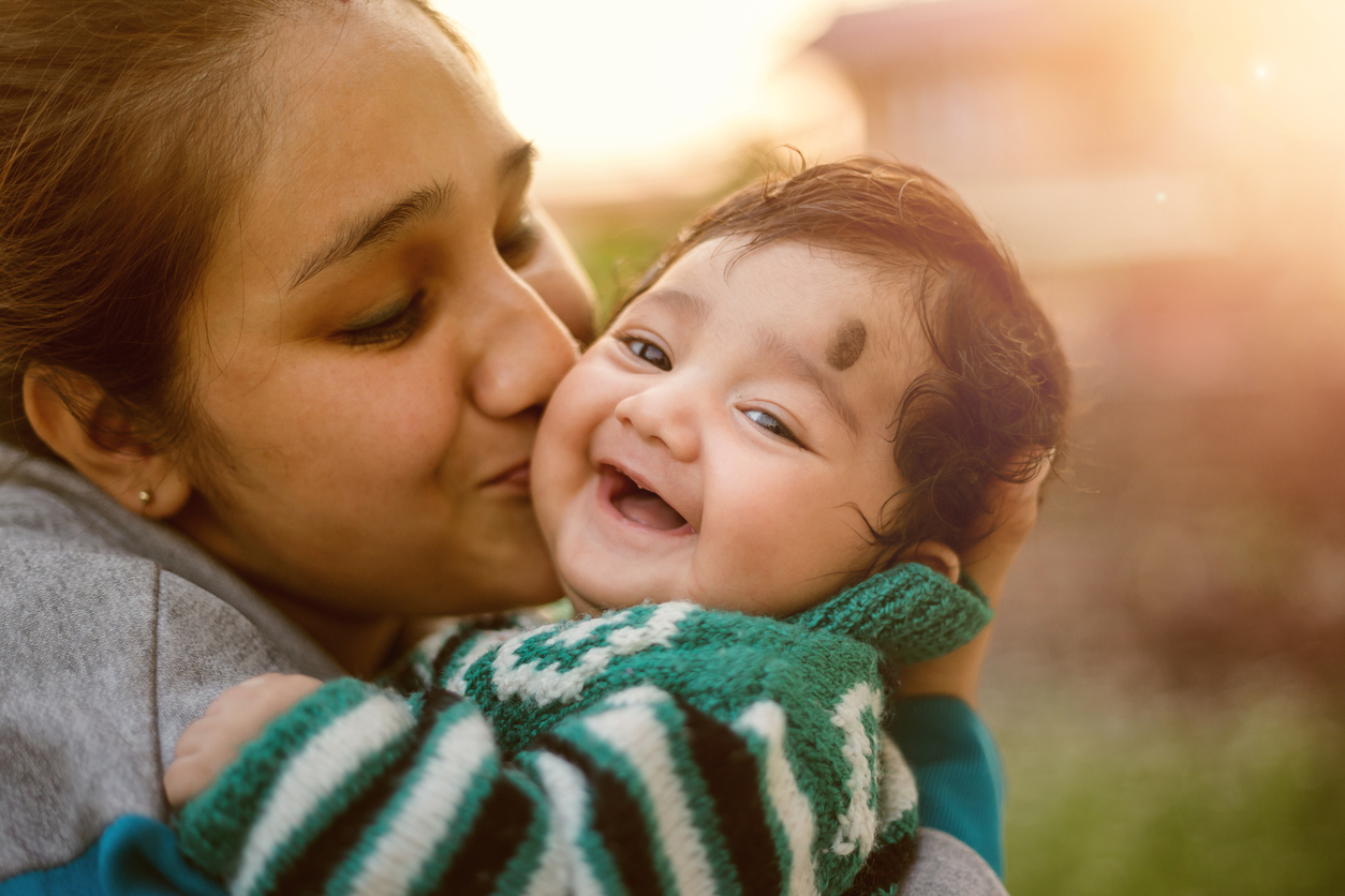 Mom Kisses Smiling Baby Son