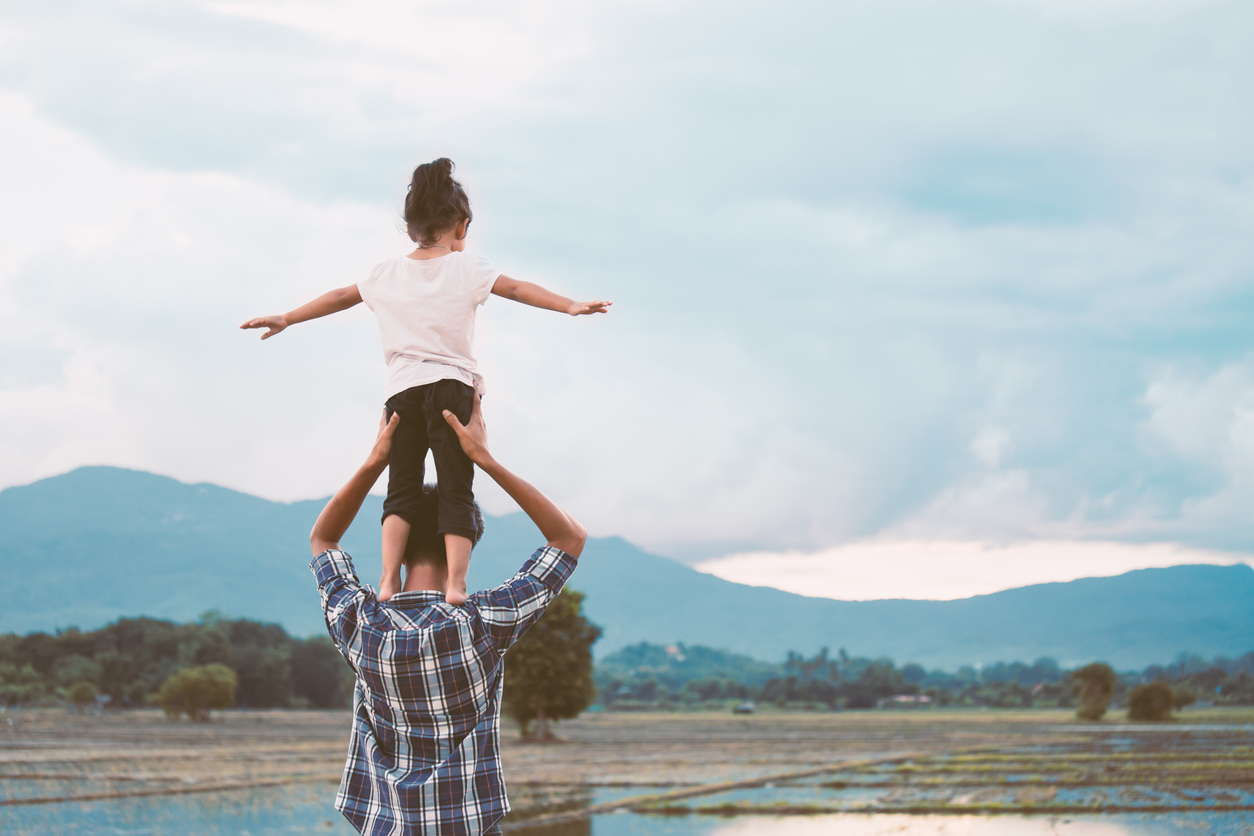 asian little girl standing on father's shoulder and playing together