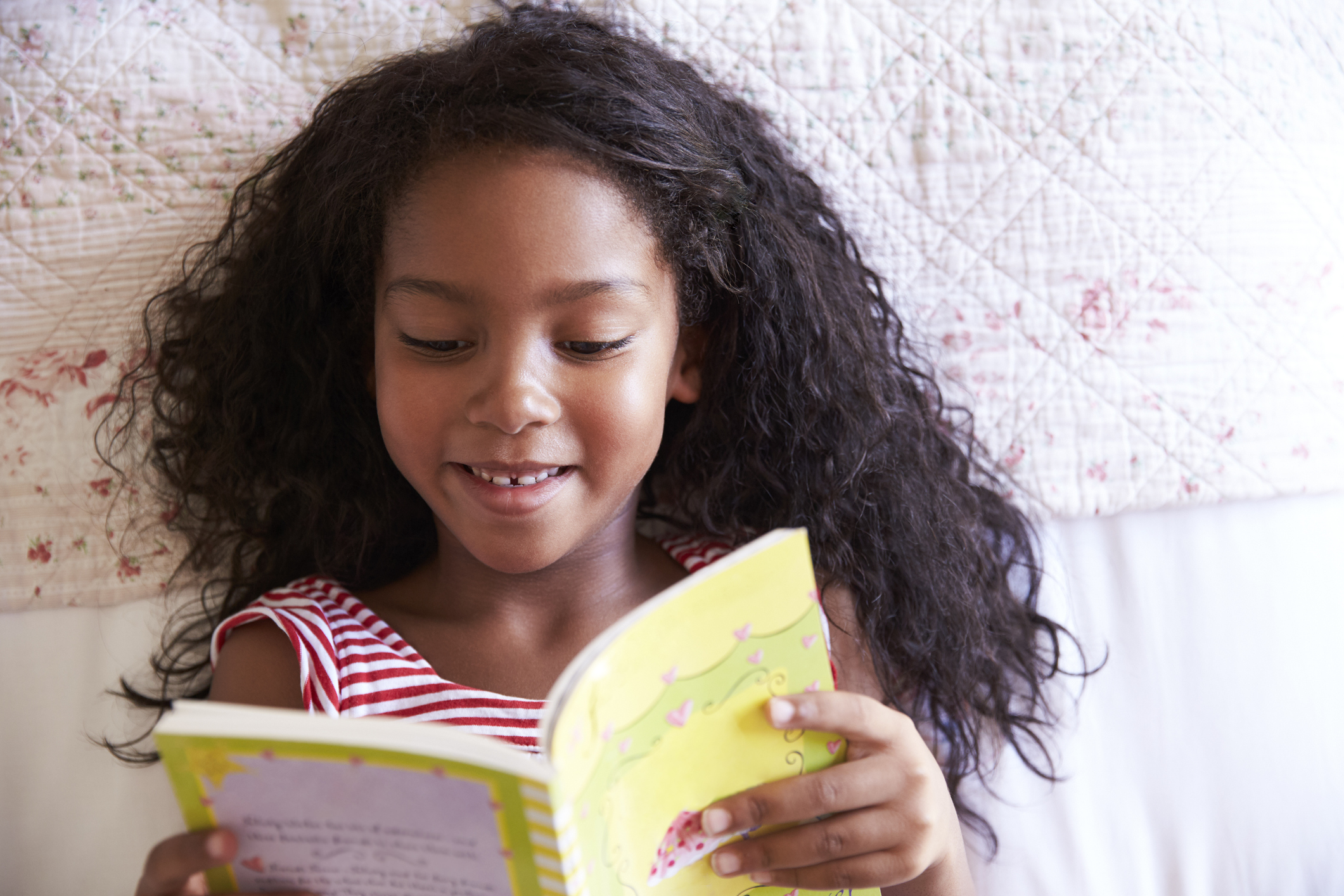 Overhead View Of Girl Lying On Bed And Reading Book