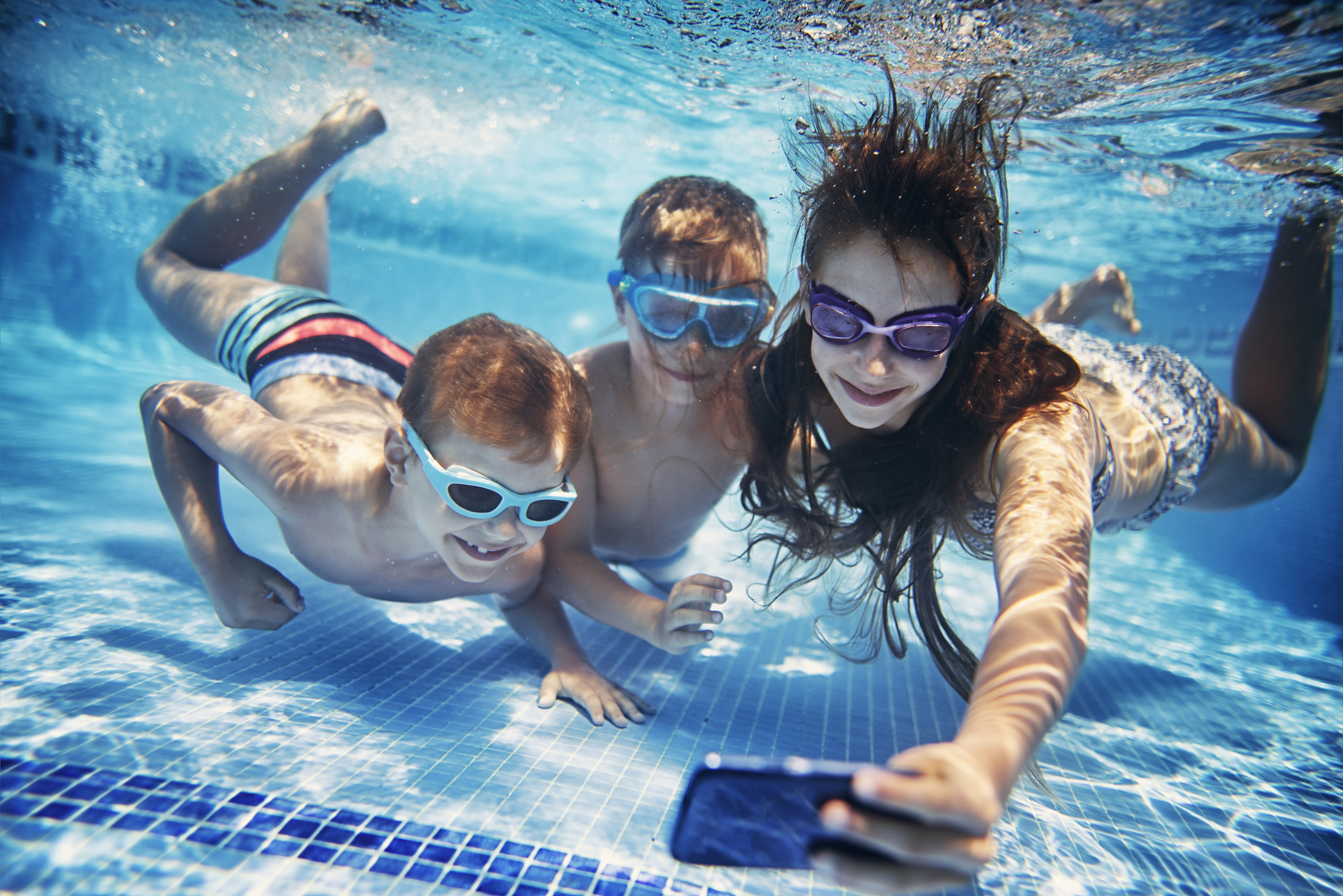 Three happy kids taking selfies underwater