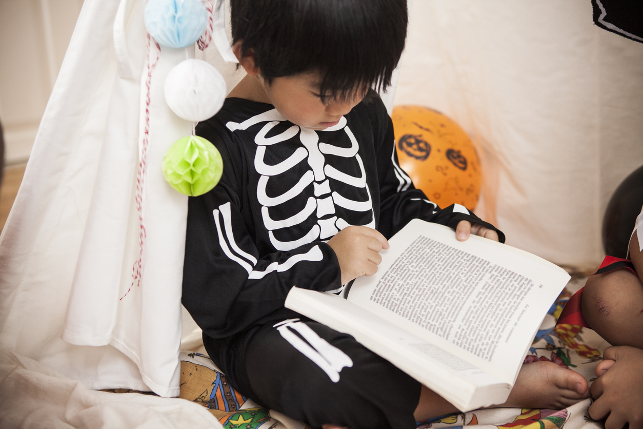 A boy wearing a costume reads a book.