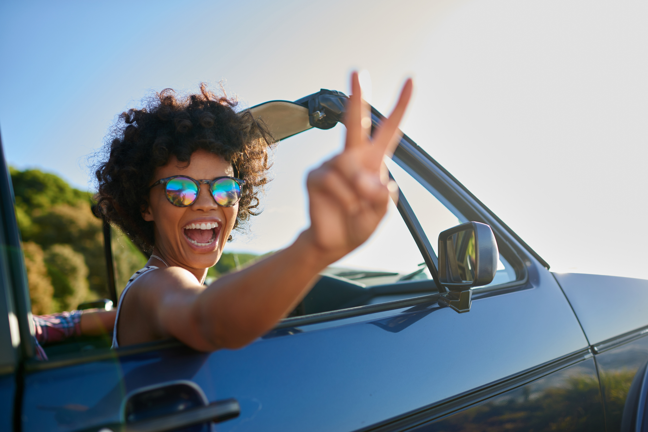 Young woman leaning out the window of car