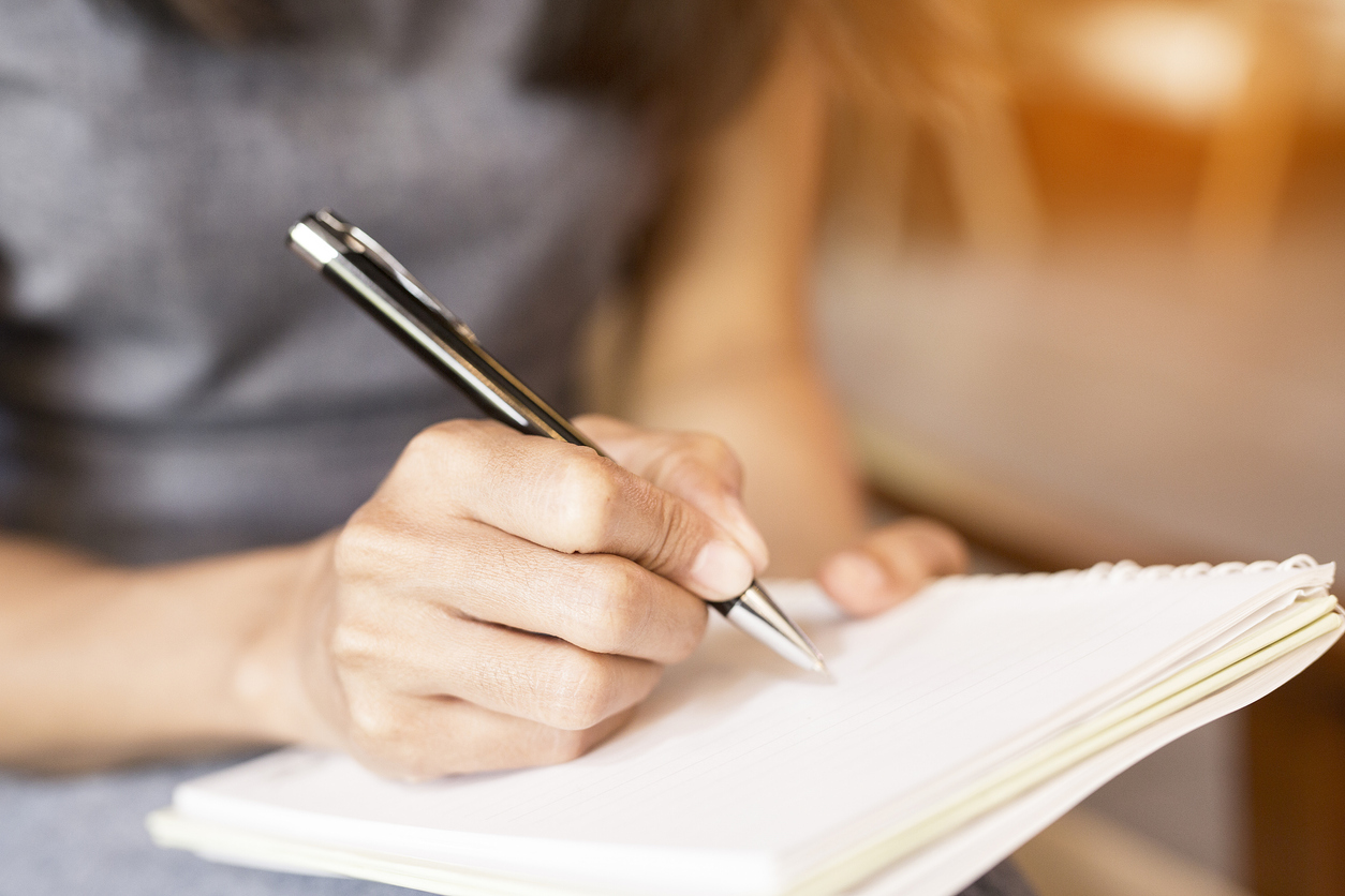 Women holding a pens writing a notebook. Recording concept