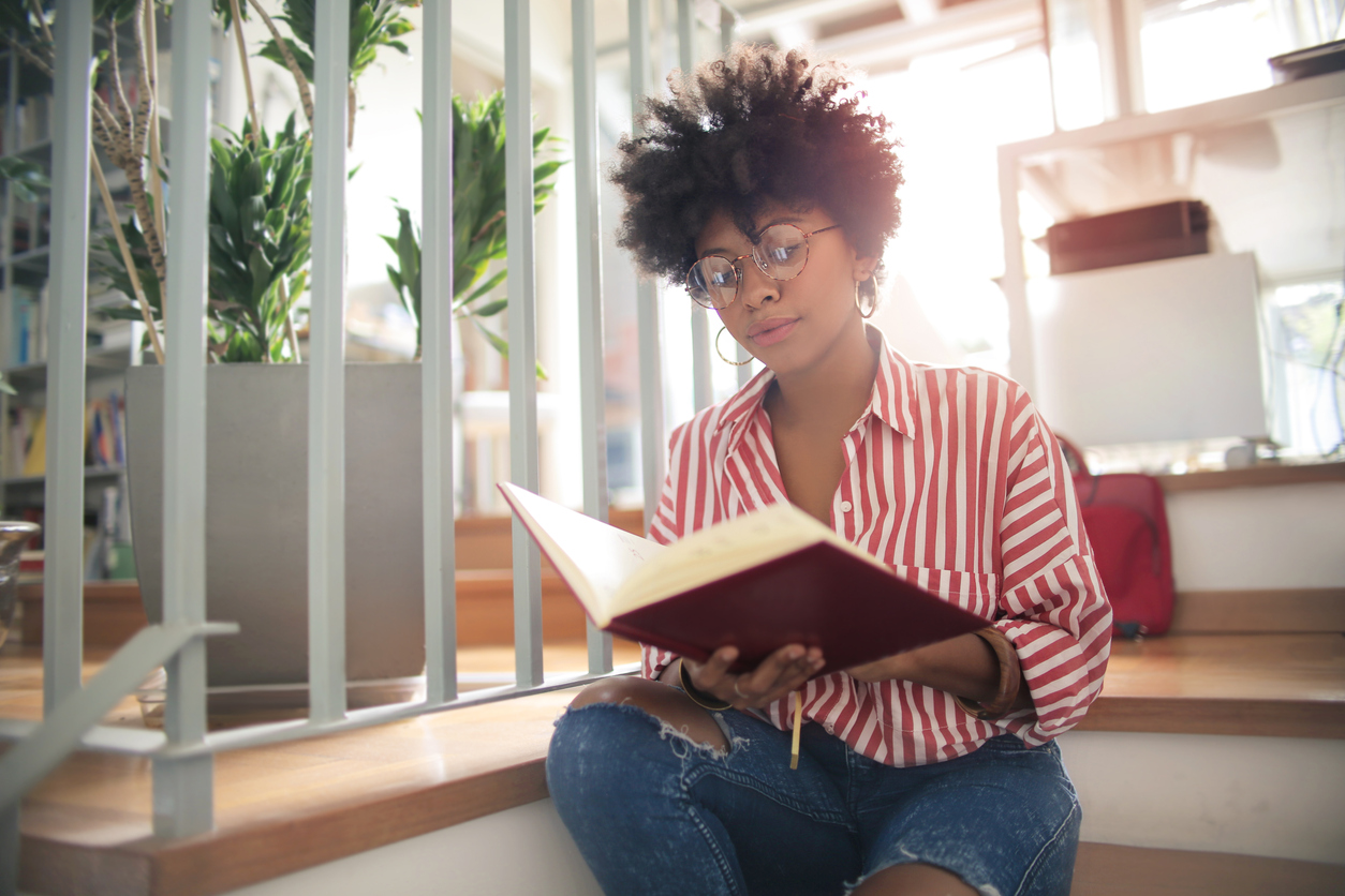 Girl reading a book, sitting on home's stairs