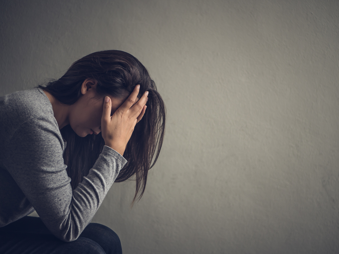 Depressed woman sitting on a chair in dark room at home. Lonly , sad, emotion concept.