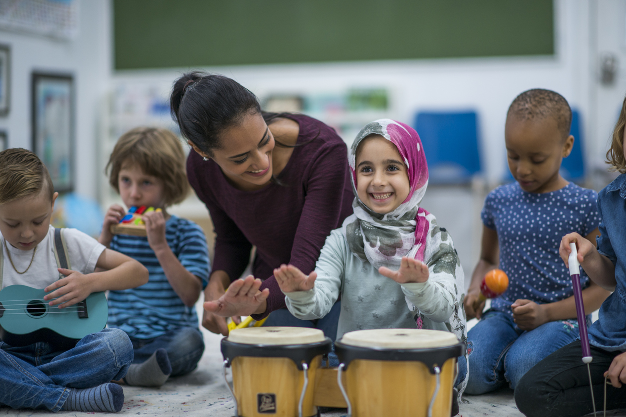 Little Muslim girl enjoy music class at school with her friends.