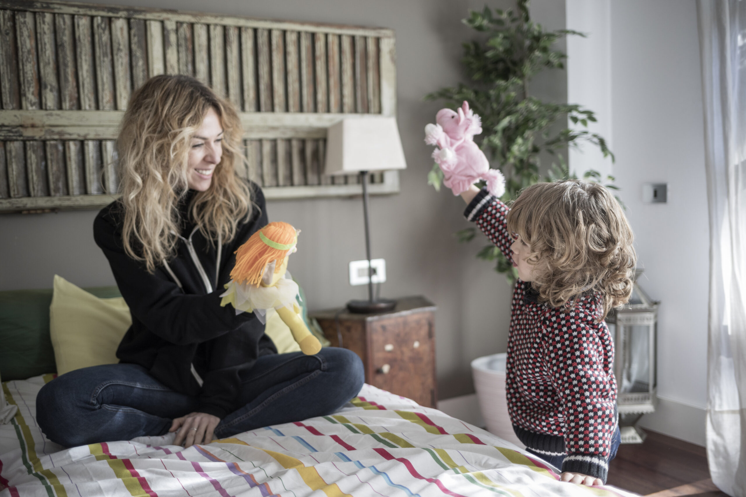 Mother playing with puppets with her son at home