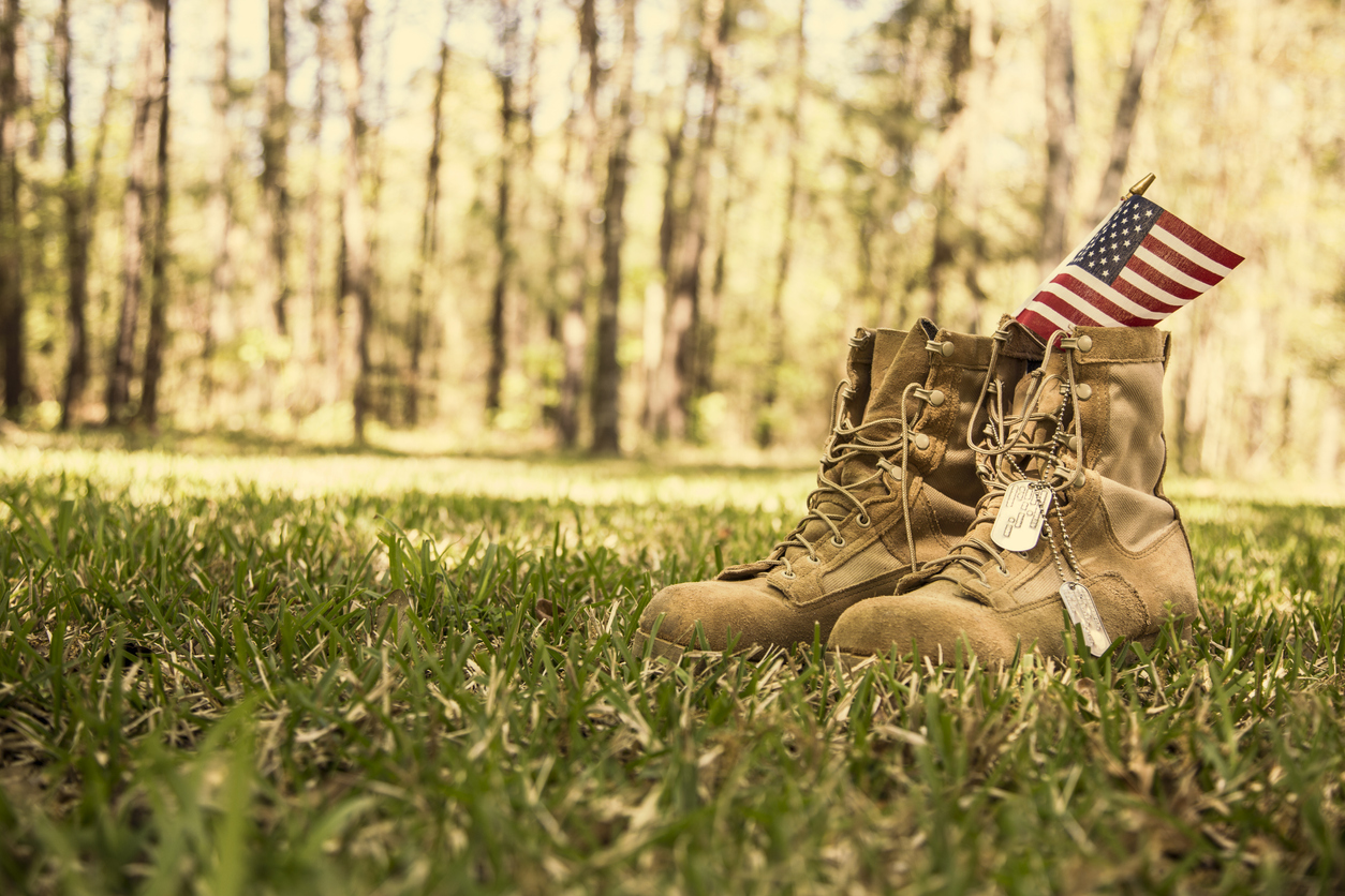 USA Military boots, flag, and dog tags outdoors.