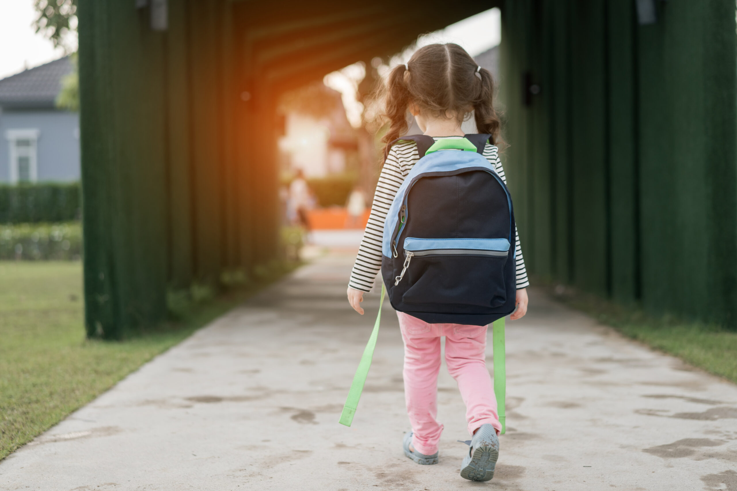 Kid girl pupil walking back to home after learning study school alone with schoolbag,preschool and kindergarten education concept.