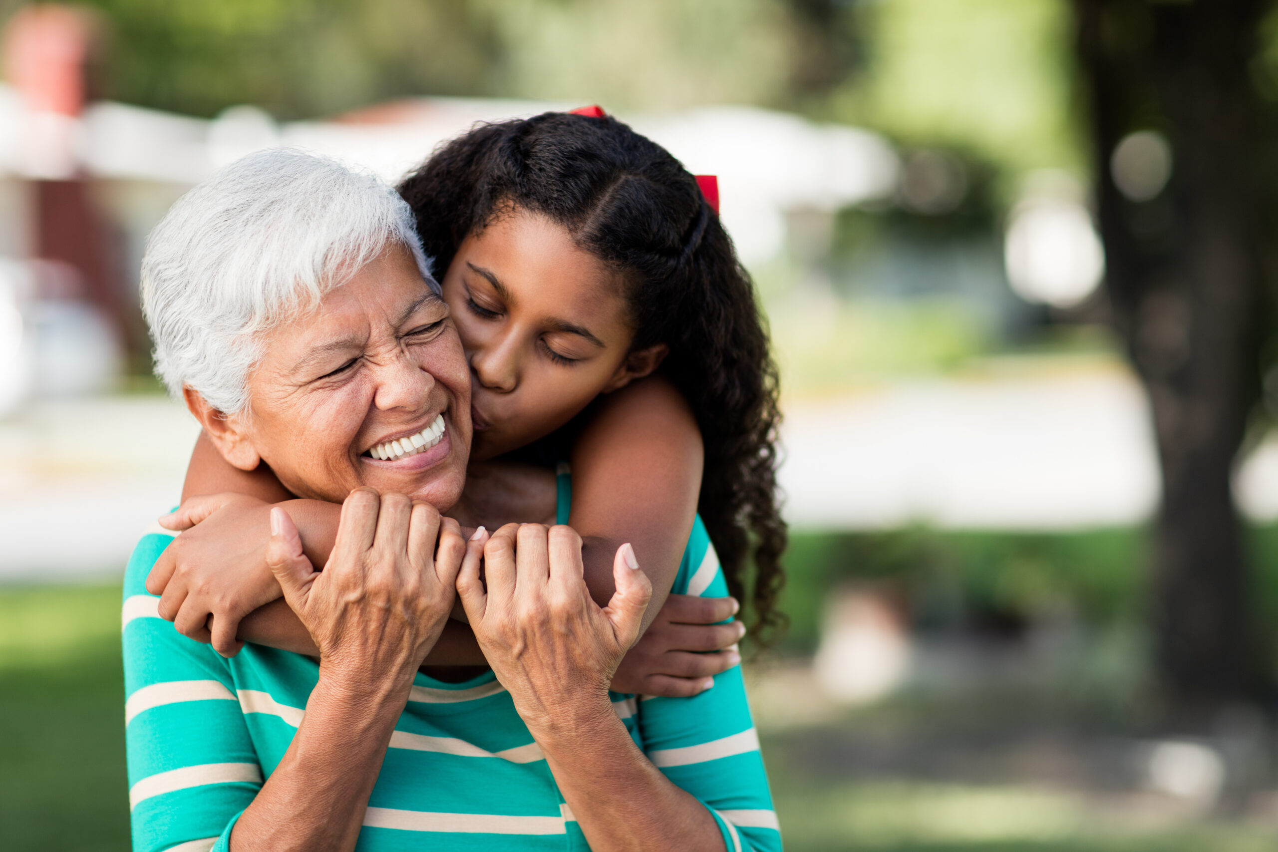 Loving teen girl embracing and kissing grandmother