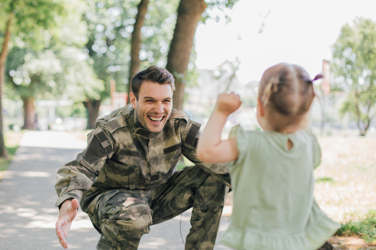 Little baby girl running towards soldier