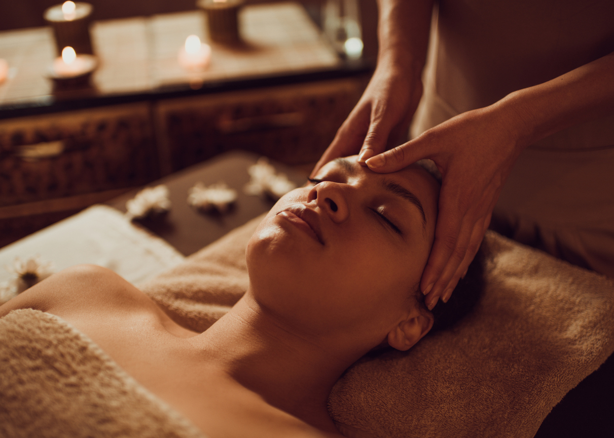 Serene African American woman receiving head massage at beauty spa.