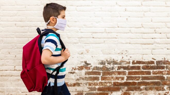 Little boy going to school with protective mask