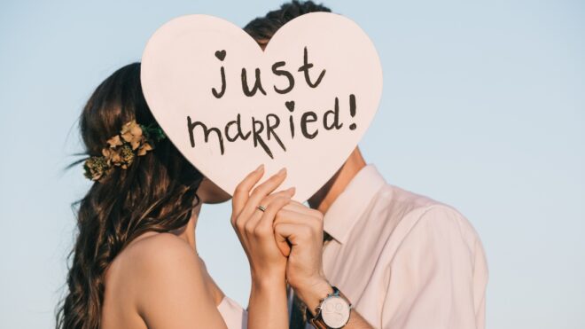 young wedding couple kissing and holding heart with just married inscription