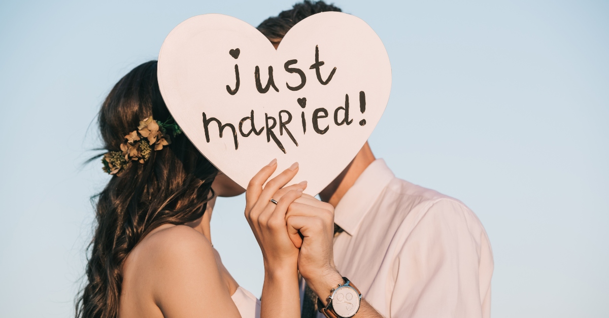 young wedding couple kissing and holding heart with just married inscription