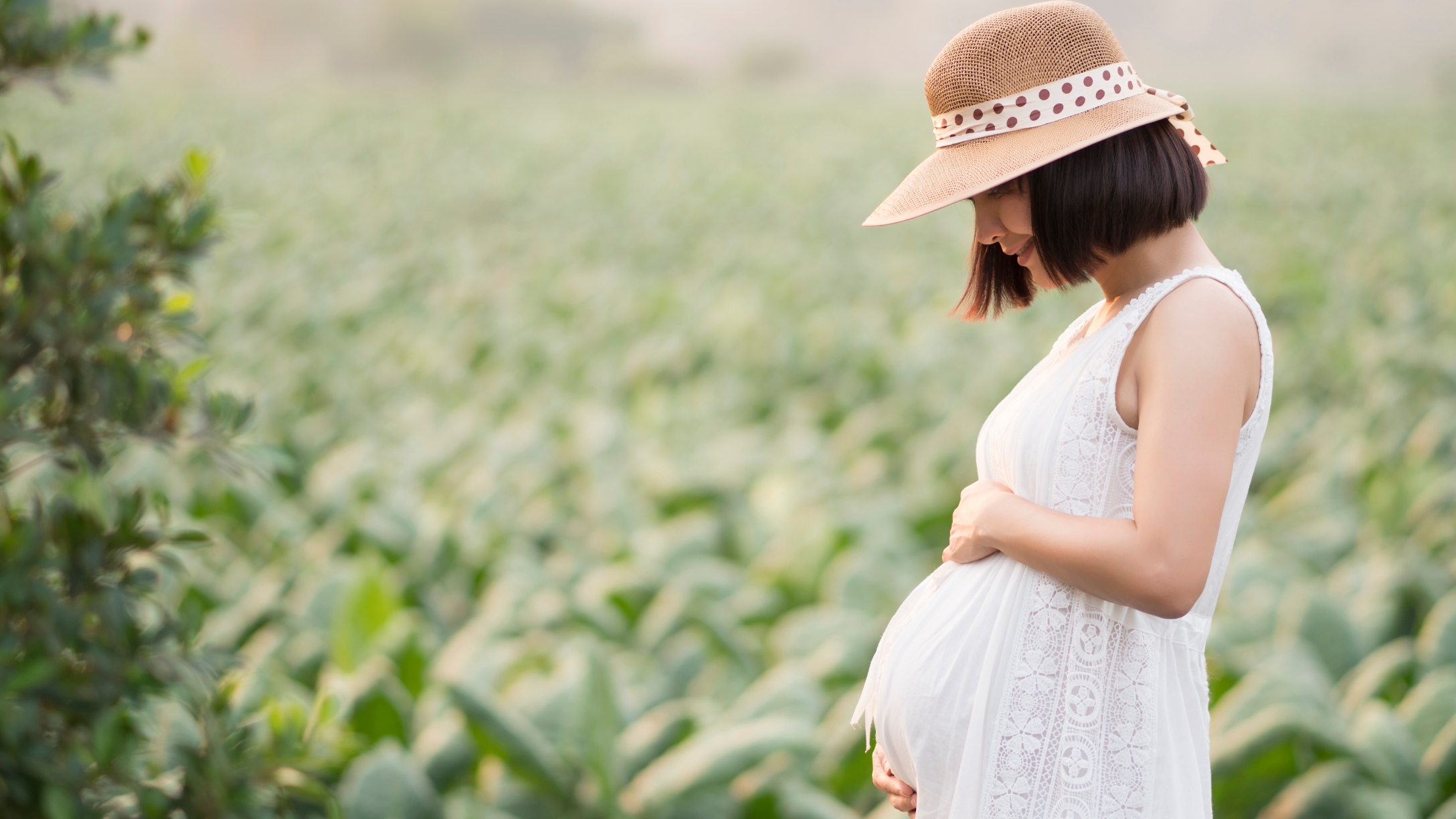 Pregnant woman touching her big belly and walking in the park