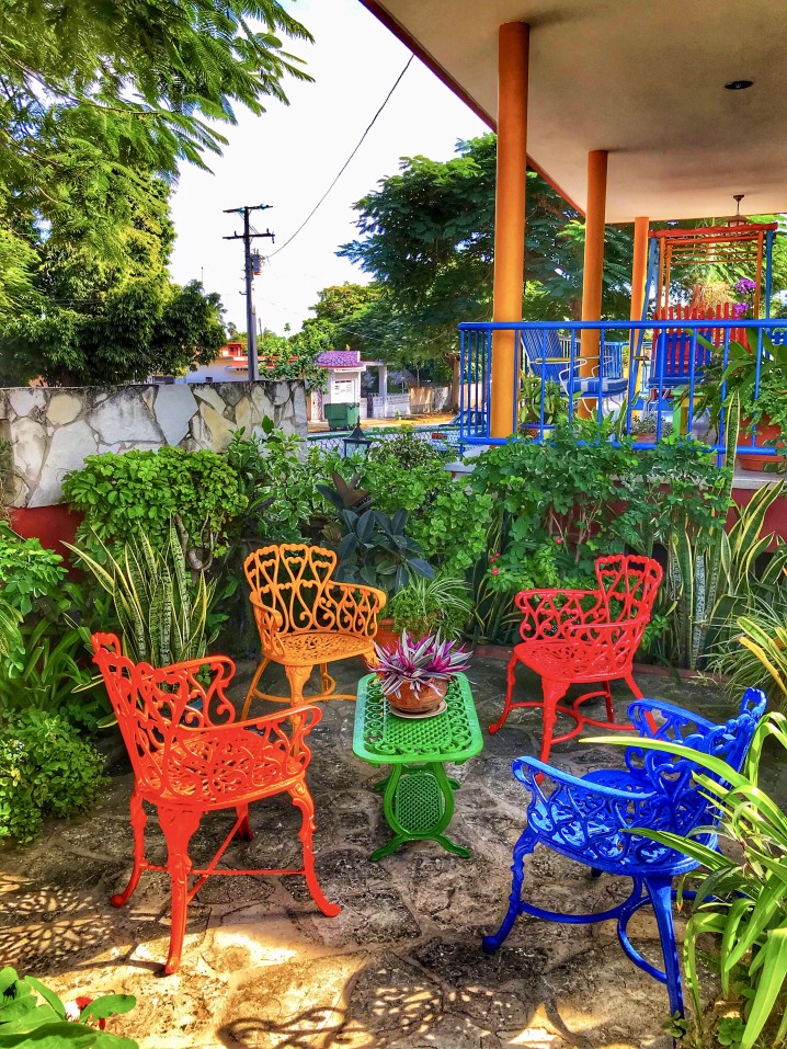 outdoor-red-blue-yellow-metal-chairs-and-green-metal-table-in-the-backyard-among-green-trees-flowers_t20_6mXEw9.jpg