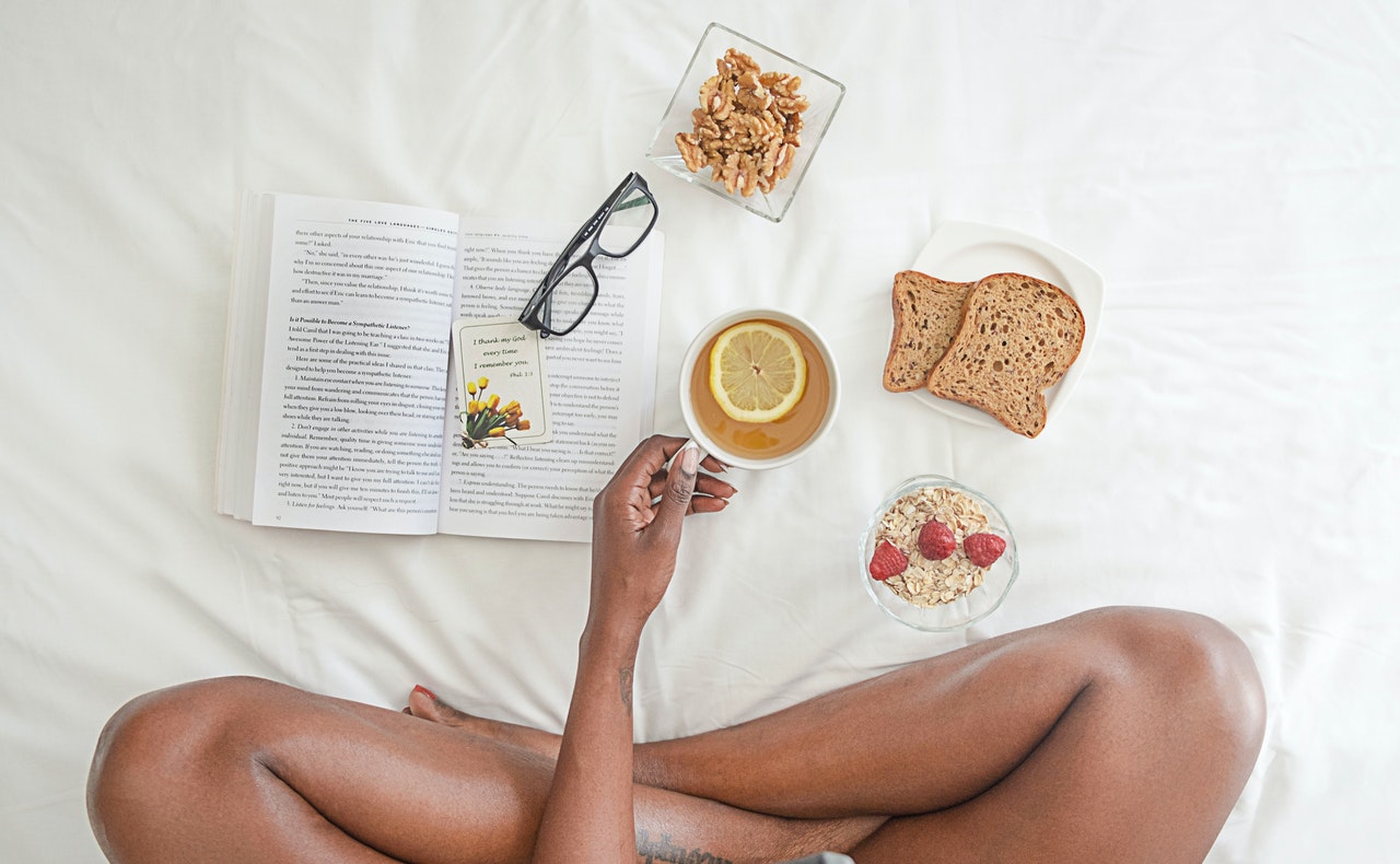 person-holding-white-ceramic-mug-with-lemon-near-book-and-1065588.jpg