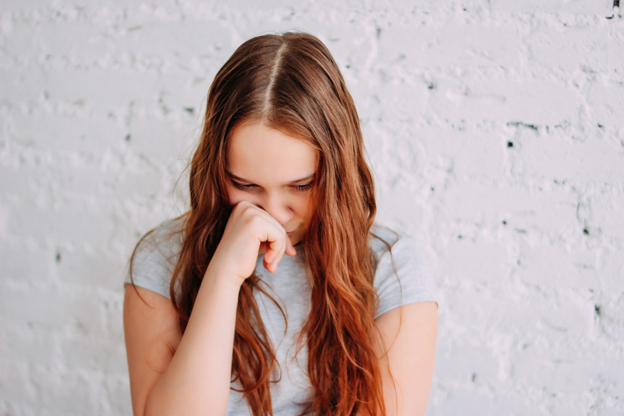 sad-teen-girl-with-long-curly-red-hair-isolated-on-white-brick-wall_t20_YwgowO.jpg