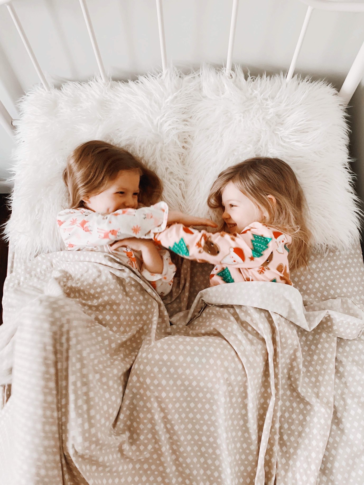 two-little-girls-are-laying-in-bed-in-their-christmas-pajamas-they-are-covered-in-a-pink-blanket-with_t20_G0eaLm.jpg