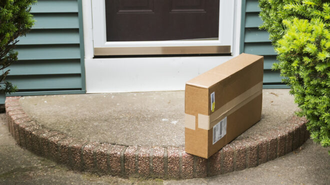 A brown cardboard box is left on the front stoop after being delivered while no one was home.