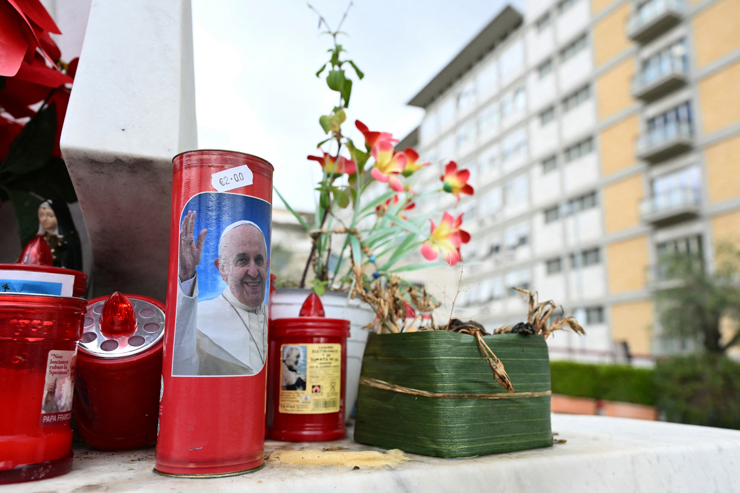 A candle with a picture of Pope Francis is set at the bottom of a statue of Pope John Paul II at the Gemelli hospital where Pope Francis is hospitalized for tests and treatment for bronchitis in Rome, on Feb. 14, 2025. The 88-year-old, who has been breathless in recent days and has delegated officials to read his speeches, was admitted following his morning audiences, the Vatican announced. (Alberto Pizzoli/AFP/Getty Images/TNS)