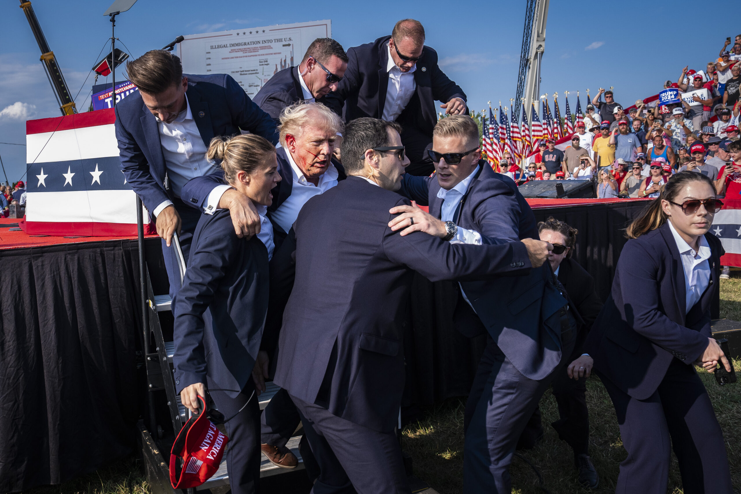 Butler, PA - July 13 : U.S. Secret Service agents remove Republican presidential candidate former president Donald Trump from the stage with blood on his face during a campaign rally at Butler Farm Show Inc. in Butler, PA on Saturday, July 13, 2024. Trump later shared that a bullet pierced part of his ear during the assassination attempt. (Photo by Jabin Botsford/The Washington Post via Getty Images)