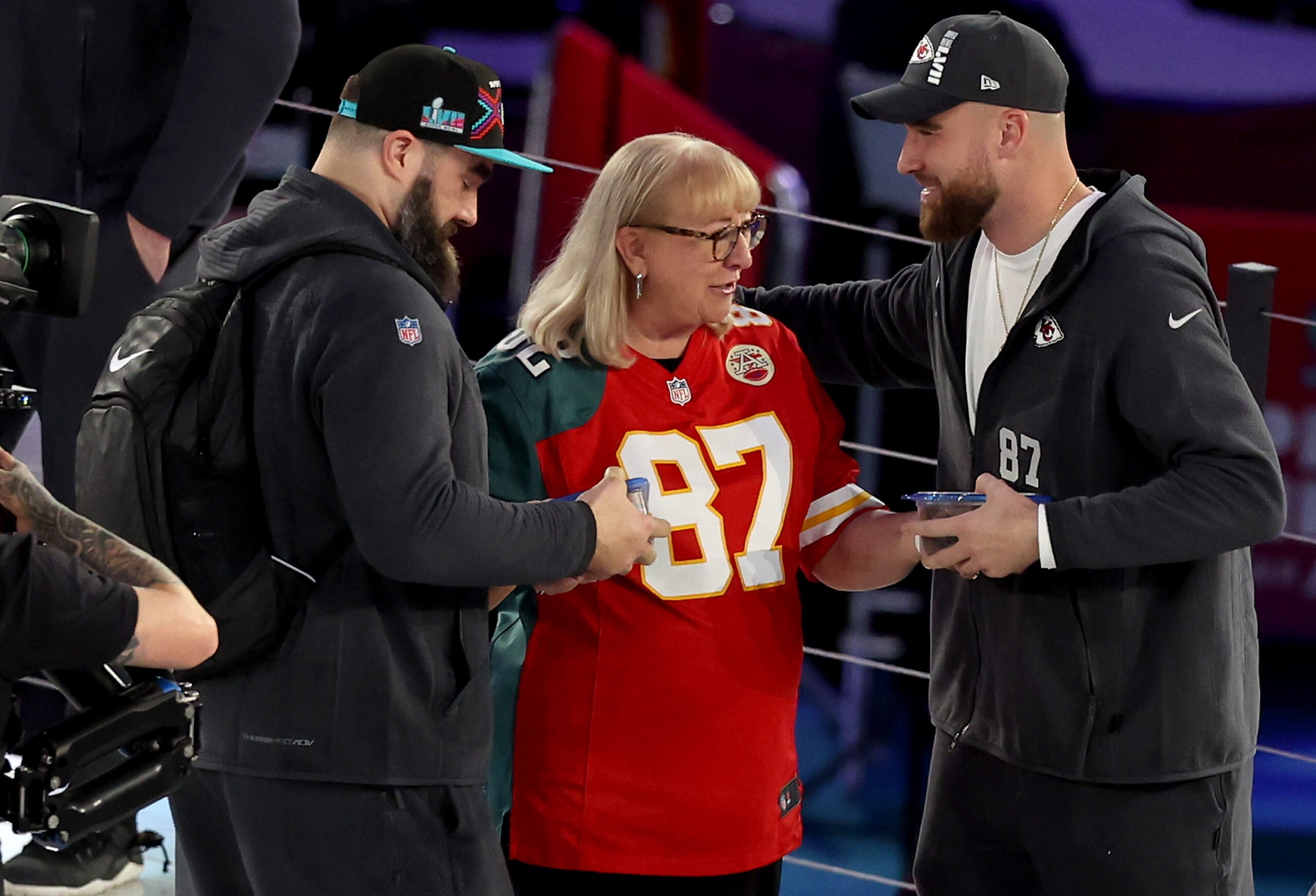 PHOENIX, ARIZONA - FEBRUARY 06: Mother Donna Kelce (C) gives cookies to her son's Jason Kelce (L) #62 of the Philadelphia Eagles and Travis Kelce (R) #87 of the Kansas City Chiefs during Super Bowl LVII Opening Night presented by Fast Twitch at Footprint Center on February 06, 2023 in Phoenix, Arizona. (Photo by Christian Petersen/Getty Images)